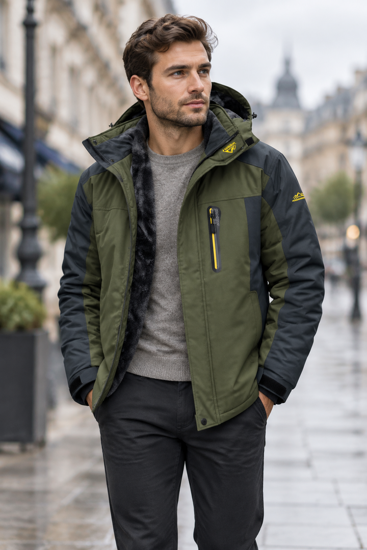 Man in an olive and charcoal hooded jacket over a grey jumper on a rainy city street 1