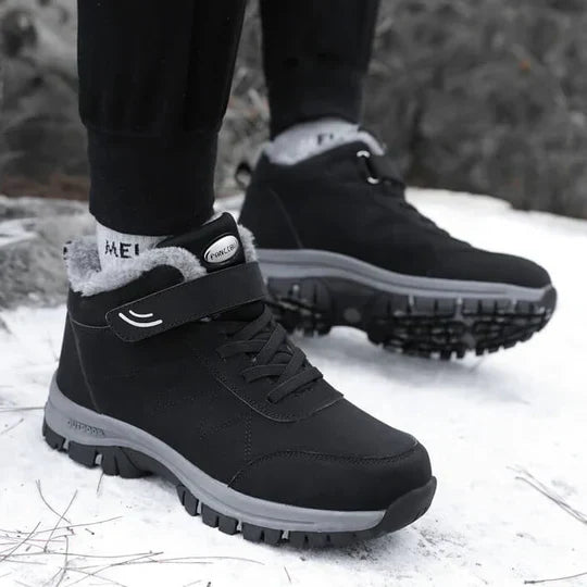 Person wearing black fleece-lined boots with strap and laces, walking on snow 4