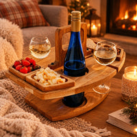 Wooden table set with wine, cheese and strawberries beside a cosy fireplace, blankets and candles 2