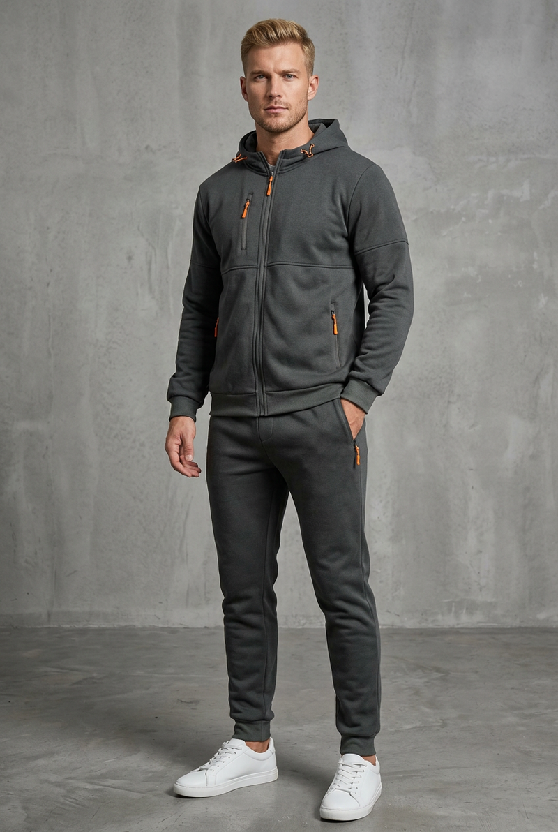 Dark grey hooded zip tracksuit with orange zip pulls, worn by a model, front view, hand in pocket 4