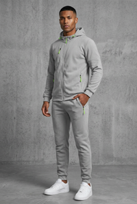 Light grey hooded zip tracksuit with neon green zip pulls, worn by a model, front view, hand in pocket 10