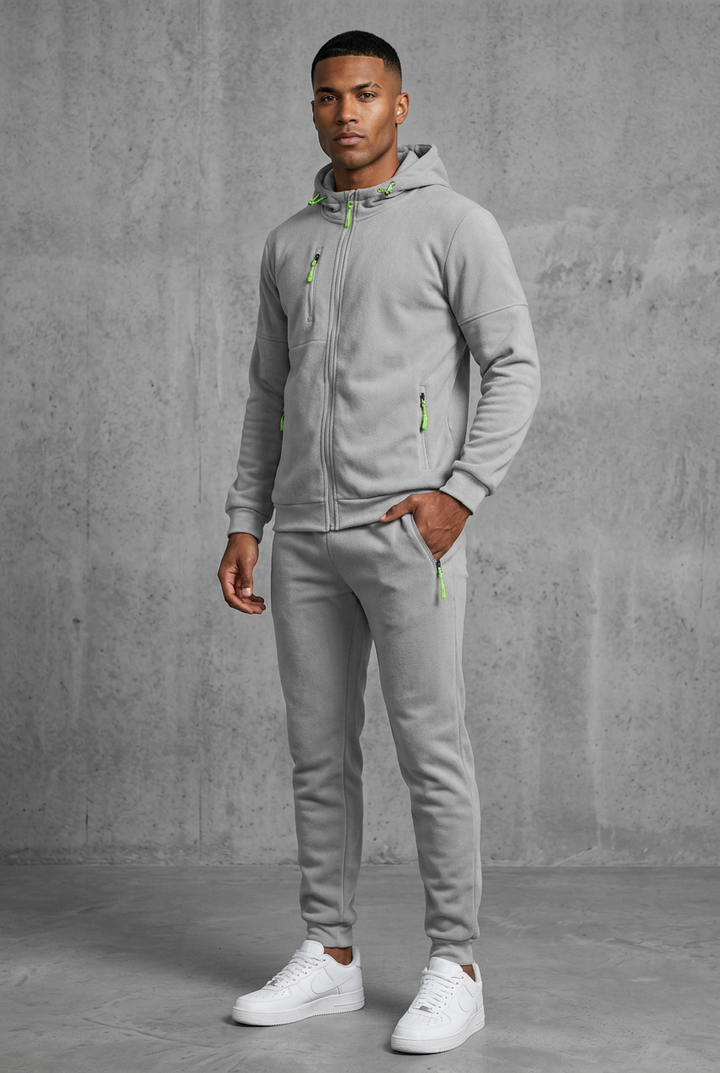 Light grey hooded zip tracksuit with neon green zip pulls, worn by a model, front view, hand in pocket 10
