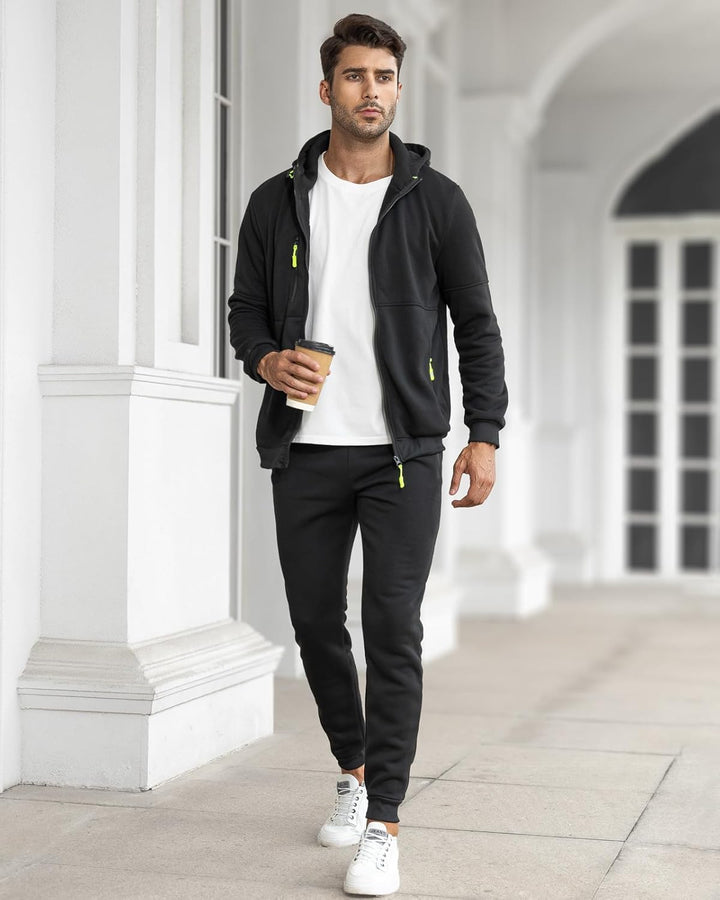 Model walking through a white colonnade in the black zip-up tracksuit with a white t-shirt, holding a coffee 24
