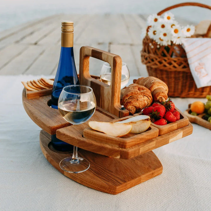 Wooden wine table on a blanket beside a wicker basket of daisies, with croissants, pear and strawberries 8