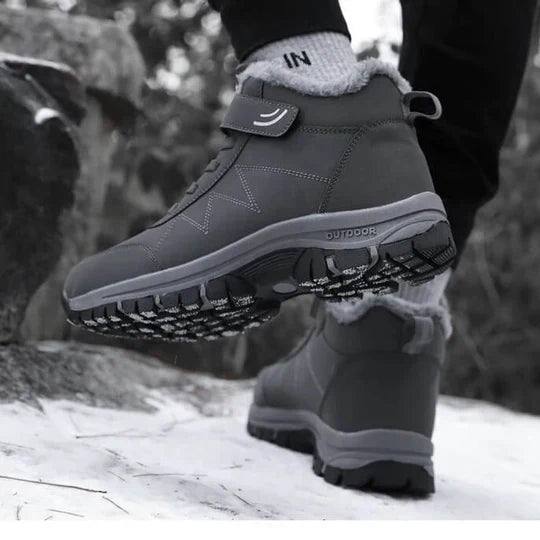 Person wearing grey fleece-lined boots on snowy ground, lifted sole showing the patterned tread 8