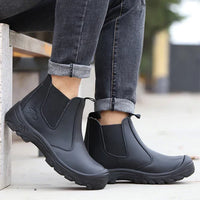 Model in rolled grey jeans sitting on a bench, wearing black leather pull-on boots with thick treaded soles 8