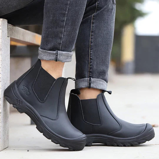 Model in rolled grey jeans sitting on a bench, wearing black leather pull-on boots with thick treaded soles 8