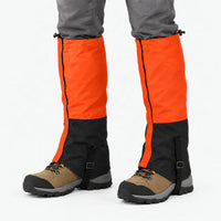 Orange and black gaiters worn over hiking boots on a white background, with side zip and instep straps 12