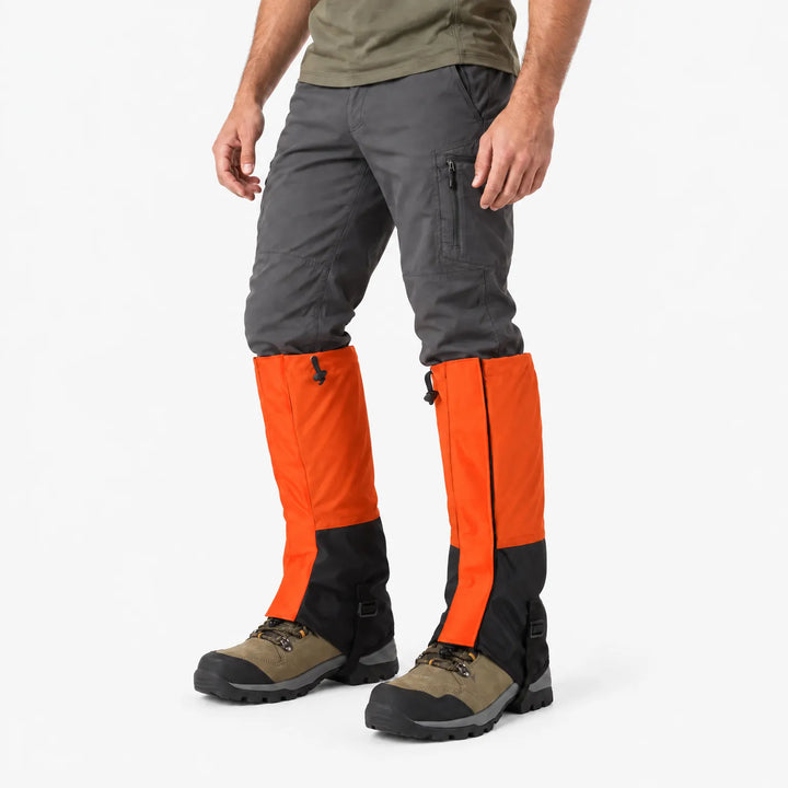 Angled side view of a model wearing orange and black gaiters over hiking boots with a black buckled instep strap 4