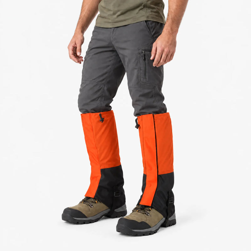 Angled side view of a model wearing orange and black gaiters over hiking boots with a black buckled instep strap 4