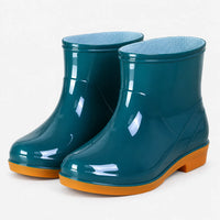Pair of glossy teal ankle rain boots with orange soles at a three-quarter angle, showing the blue mesh lining. 2