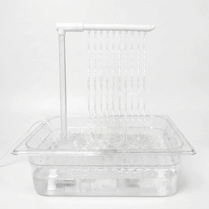 Clear tray filled with water on a plain white background, with a white overhead arm releasing ten thin streams that splash below. 1