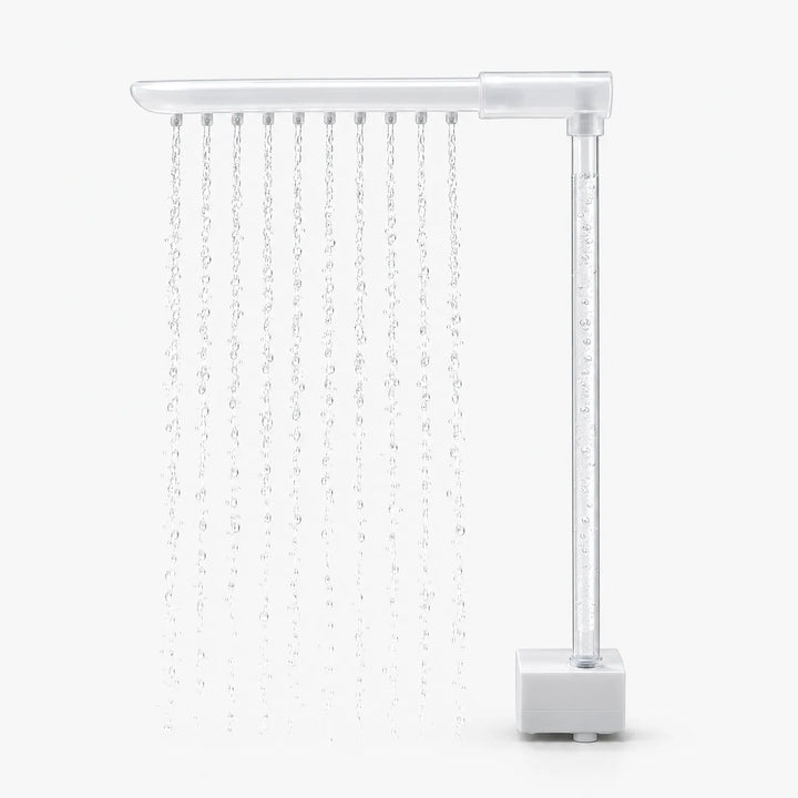 Side view of the spray arm and clear upright tube with rising bubbles, the water falling in even streams beside the pump base. 4