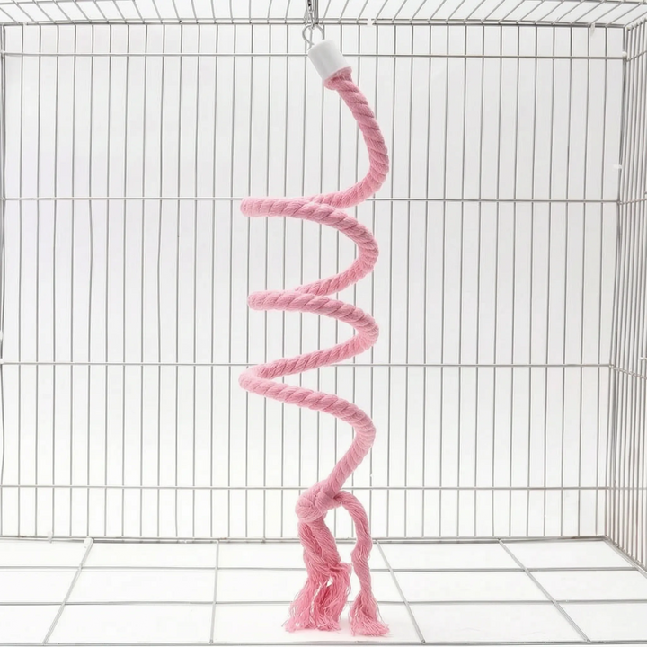 Pink version of the spiral rope perch hanging in a wire cage by a small hook, with a knotted, frayed end. 6