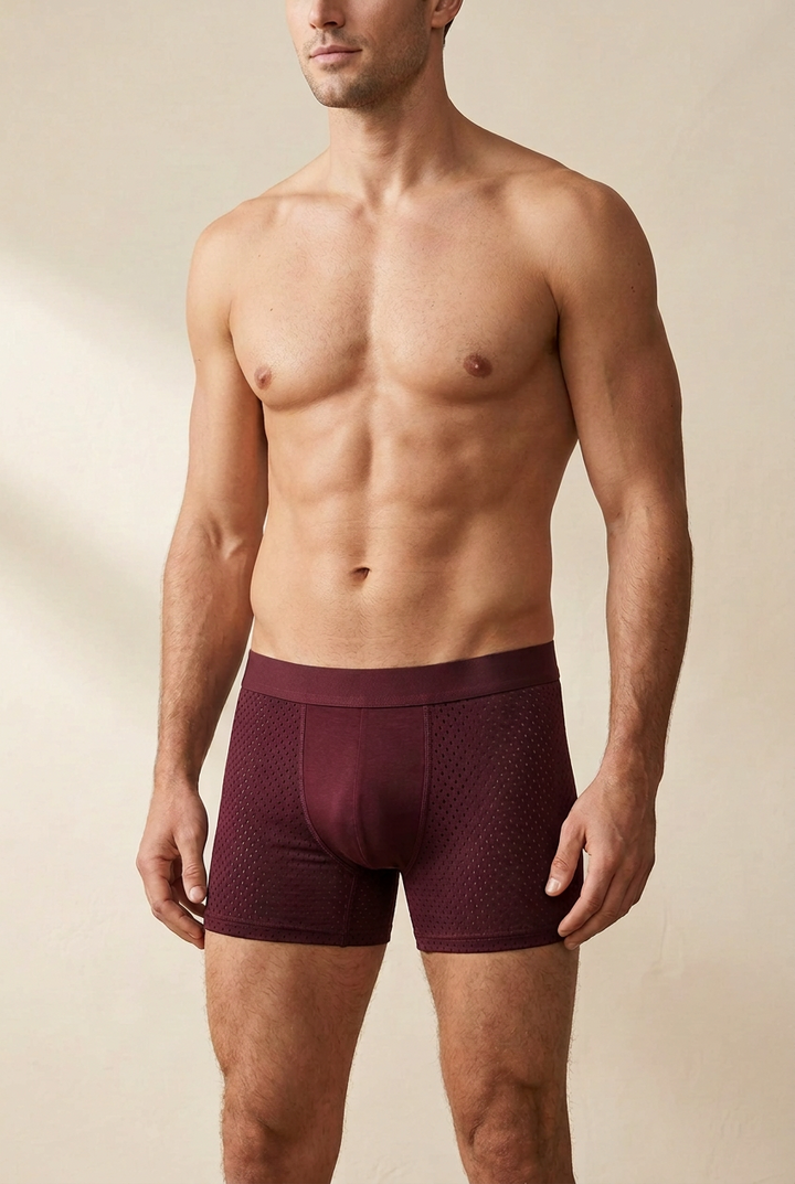Male model wearing burgundy boxer shorts with perforated mesh side panels and a plain front pouch 1