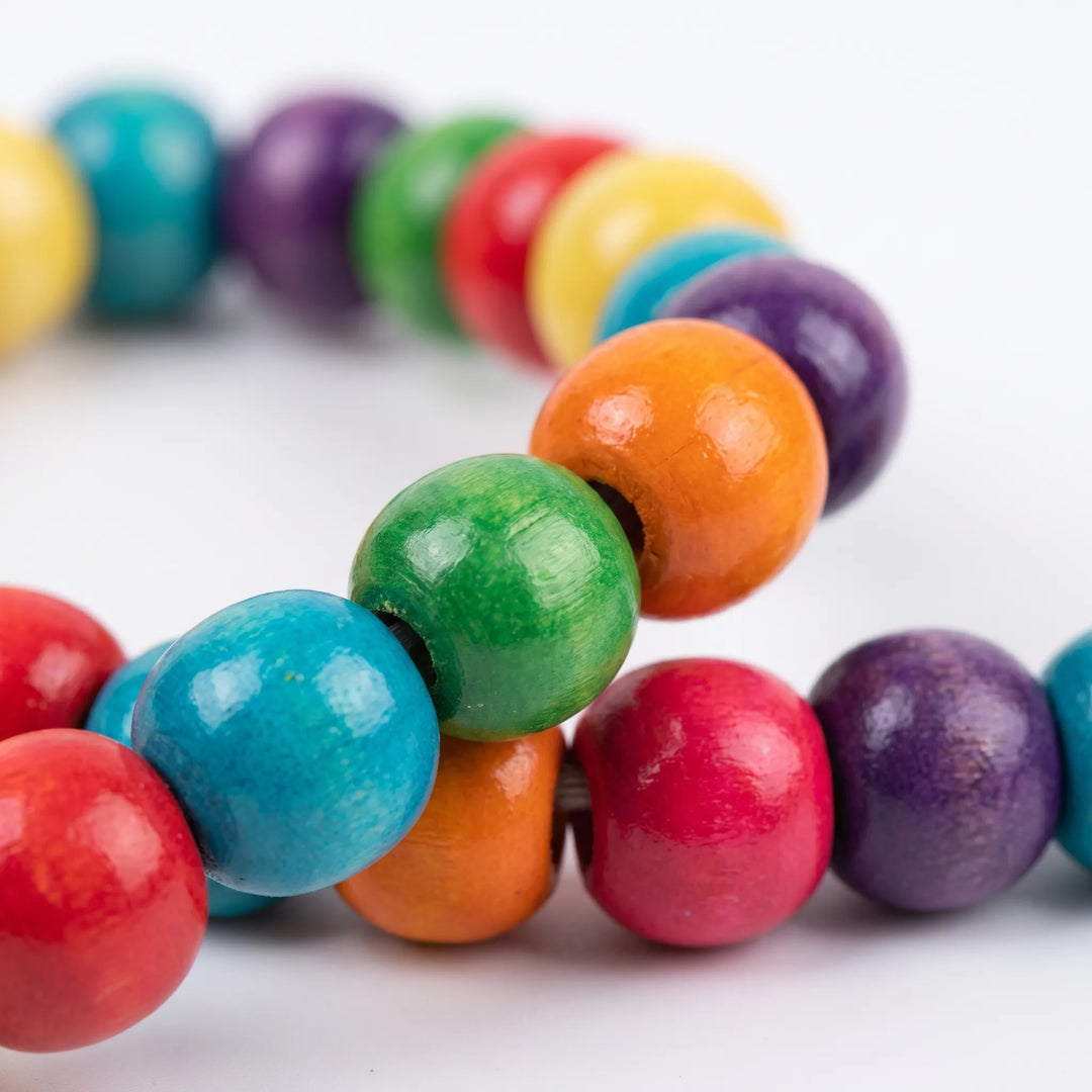 Close-up of glossy painted wooden beads in red, blue, green, orange, yellow and purple strung together. 4
