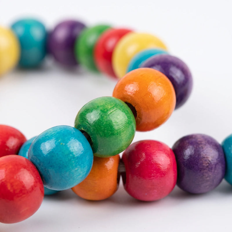 Close-up of glossy painted wooden beads in red, blue, green, orange, yellow and purple strung together. 4