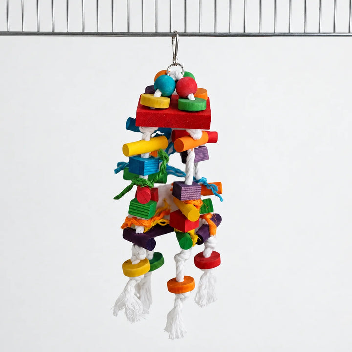 Parrot toy hanging from a cage bar by a metal clip, with coloured wooden blocks, beads and knotted white rope. 1