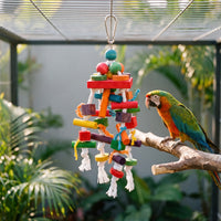 Toy hanging in an aviary beside a macaw perched on a branch, showing its size against the bird. 2