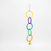Chain of five linked plastic rings in yellow, purple, blue, green and orange with a small gold bell, hanging on a white background. 1