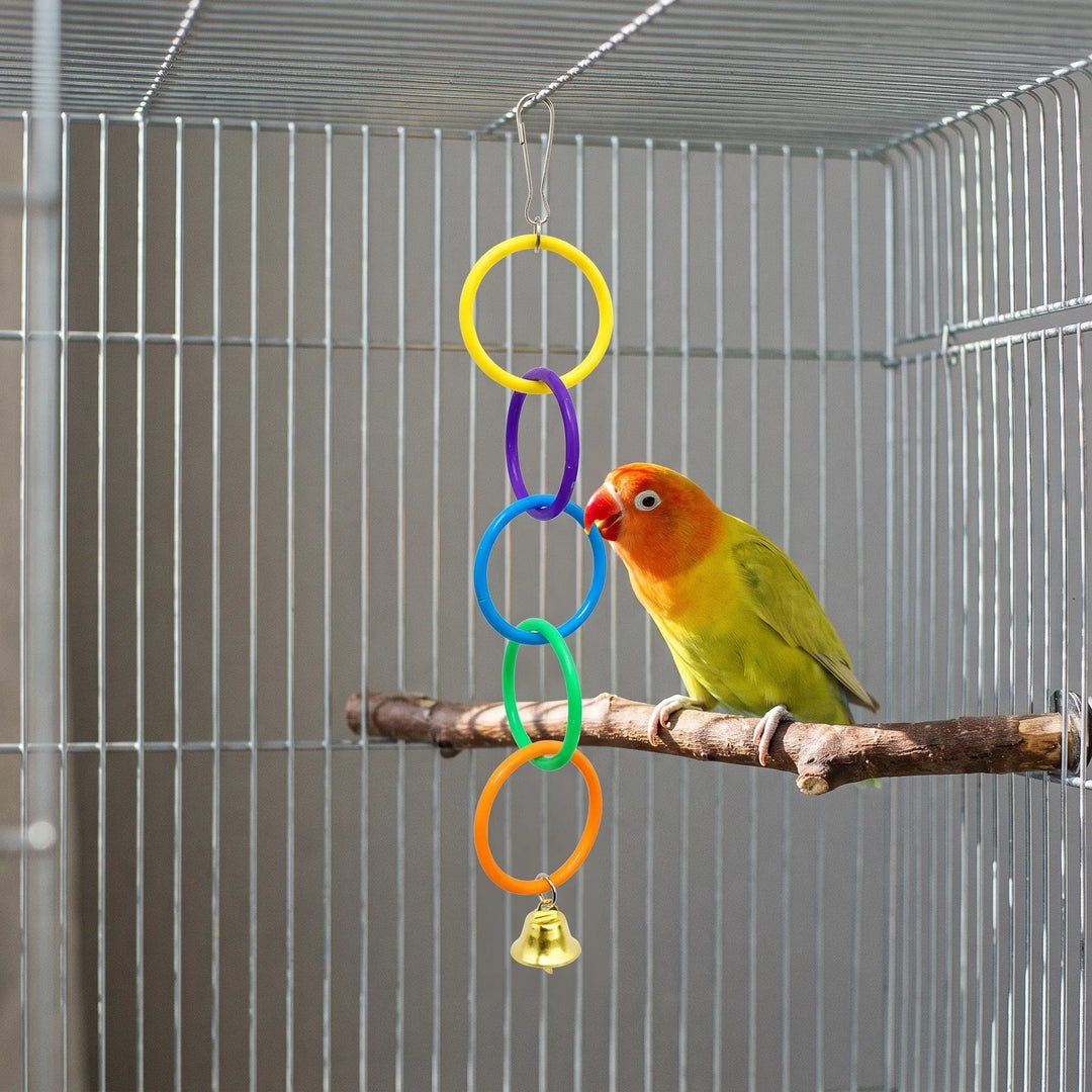 A lovebird on a wooden perch nibbling the blue ring of the hanging toy inside a metal cage. 3