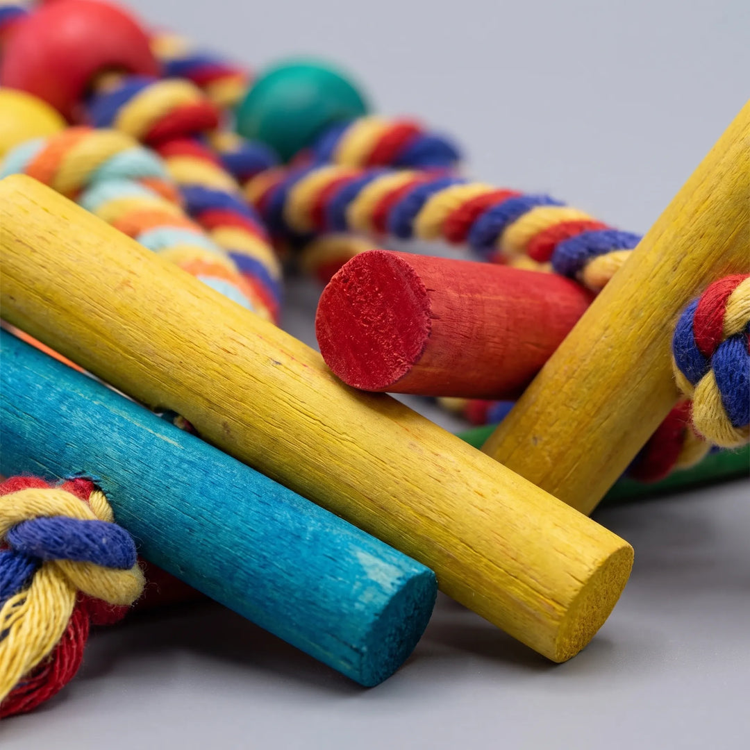 Close-up of the painted wooden dowels in yellow, red and blue, with knotted cotton rope and beads blurred behind. 3