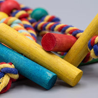 Close-up of the painted wooden dowels in yellow, red and blue, with knotted cotton rope and beads blurred behind. 3