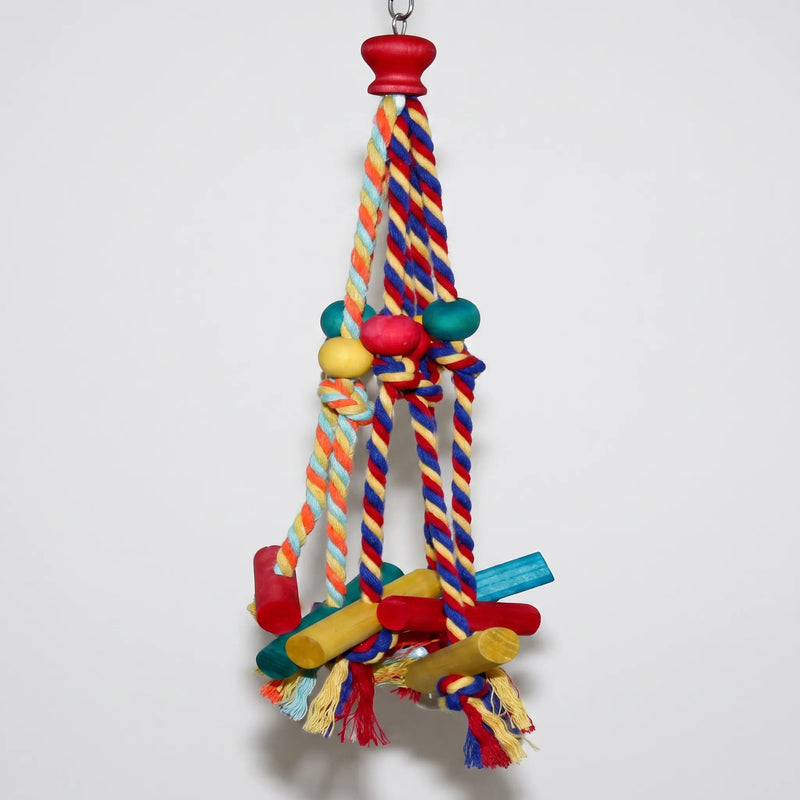 Toy hanging against a plain pale wall, showing the red wooden cap at the top, braided ropes, beads and dowels below. 4