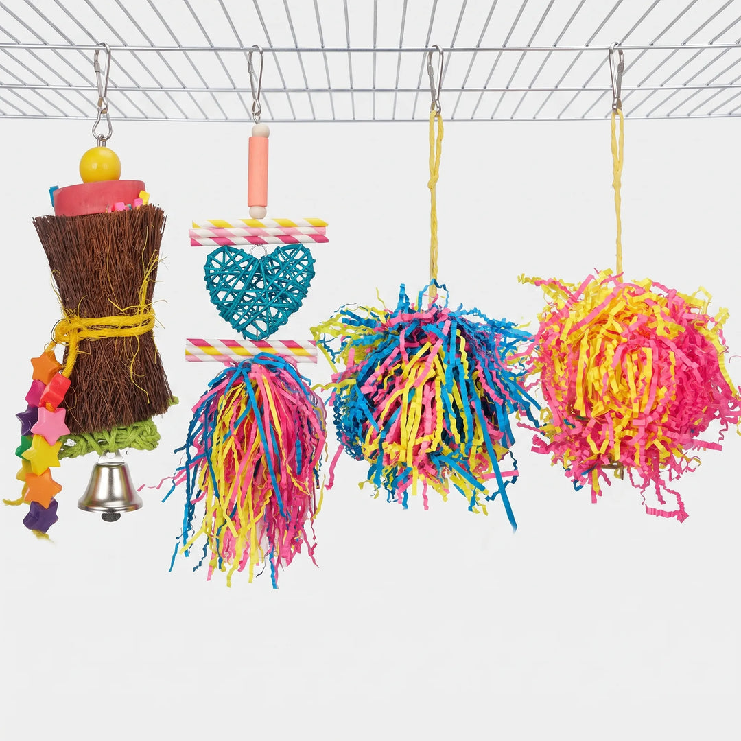 Four hanging bird toys side by side: the fibre bundle with stars and bell, a heart and paper-straw toy, and two shredded paper pom-poms. 7