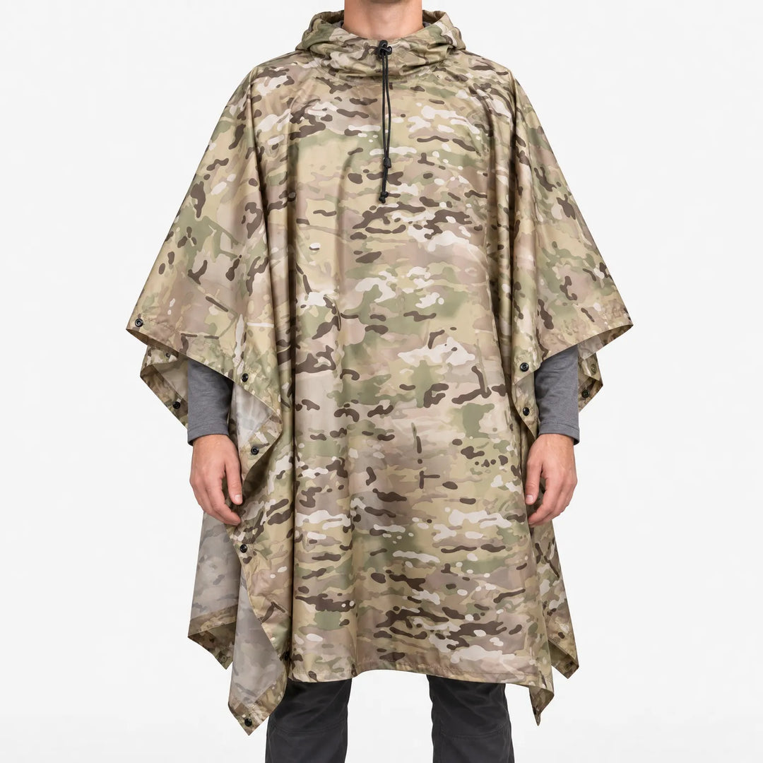 Front view of the hooded poncho in a tan, green and brown multi-terrain camouflage pattern on a model against white. 2