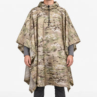 Front view of the hooded poncho in a tan, green and brown multi-terrain camouflage pattern on a model against white. 2