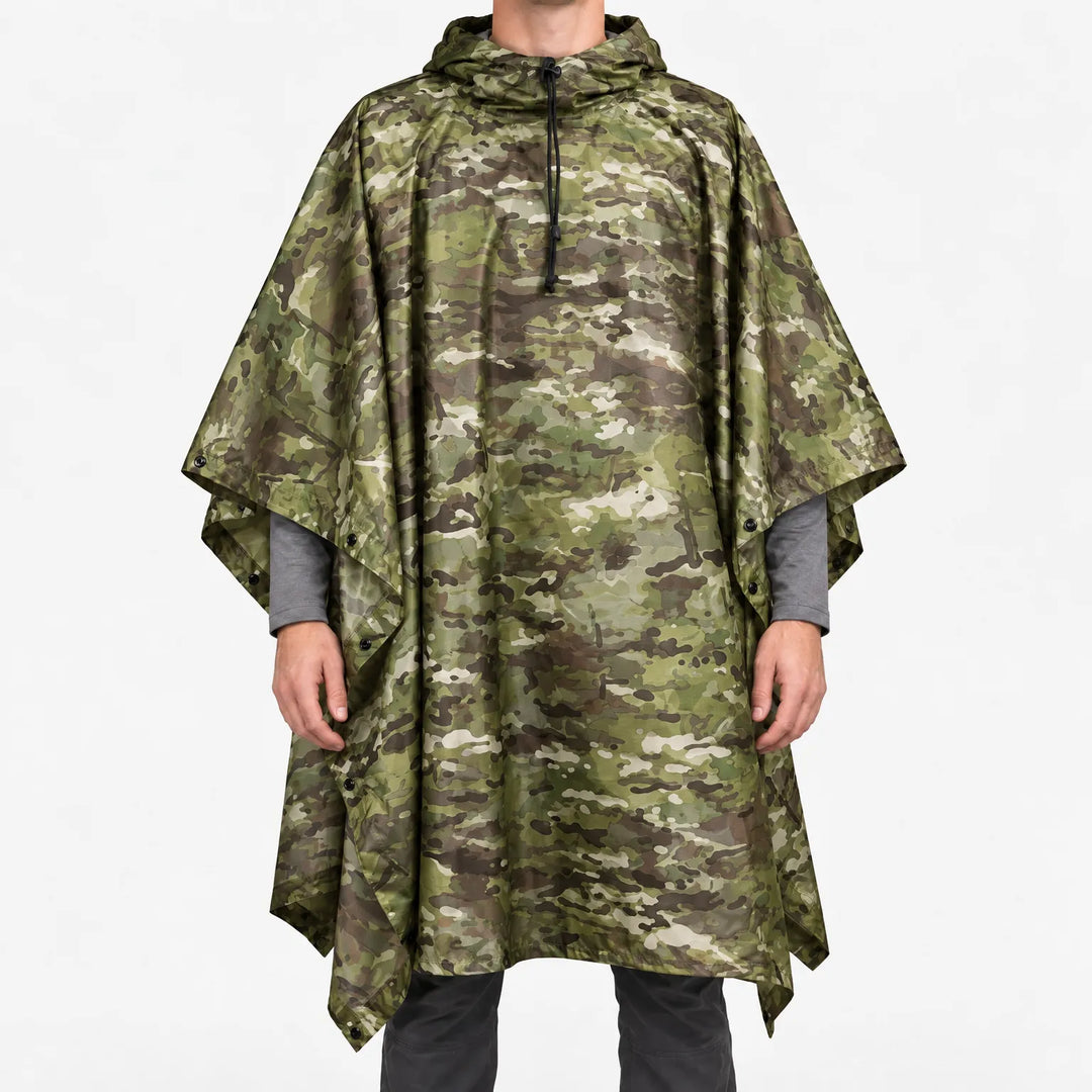 Front view of the hooded poncho in a green, brown and tan multi-terrain camouflage pattern, worn over a grey long-sleeve shirt. 7