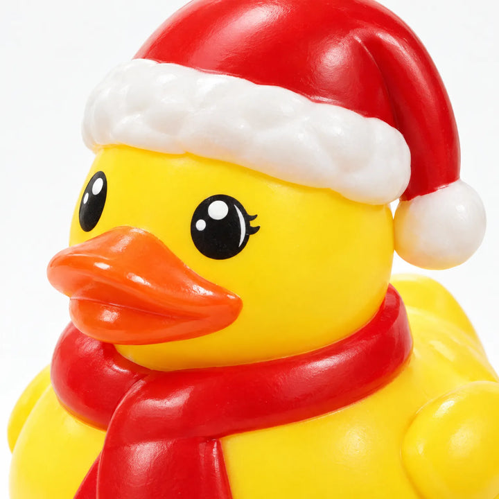 Close-up of a yellow rubber duck wearing a red Santa hat and red scarf, showing its glossy finish and painted eyes. 4