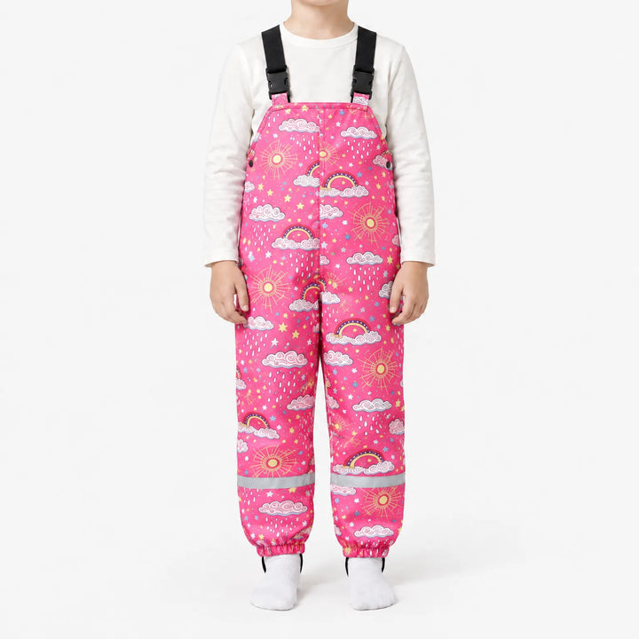 Child in bright pink dungarees printed with clouds, rainbows, suns and raindrops, with buckled shoulder straps and reflective ankle bands. 10