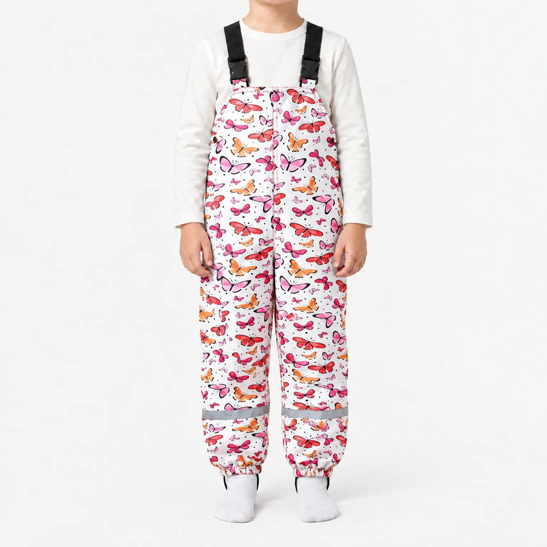 Child in white dungarees covered in pink, red and orange butterflies, with black buckled straps and a reflective strip at each ankle. 14
