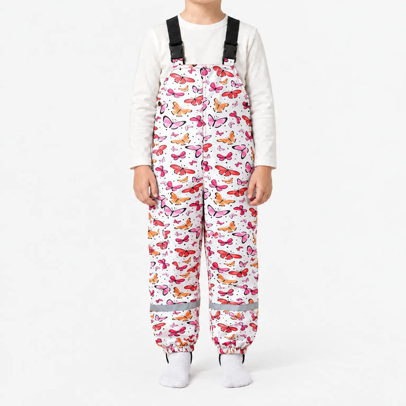 Child in white dungarees covered in pink, red and orange butterflies, with black buckled straps and a reflective strip at each ankle. 14