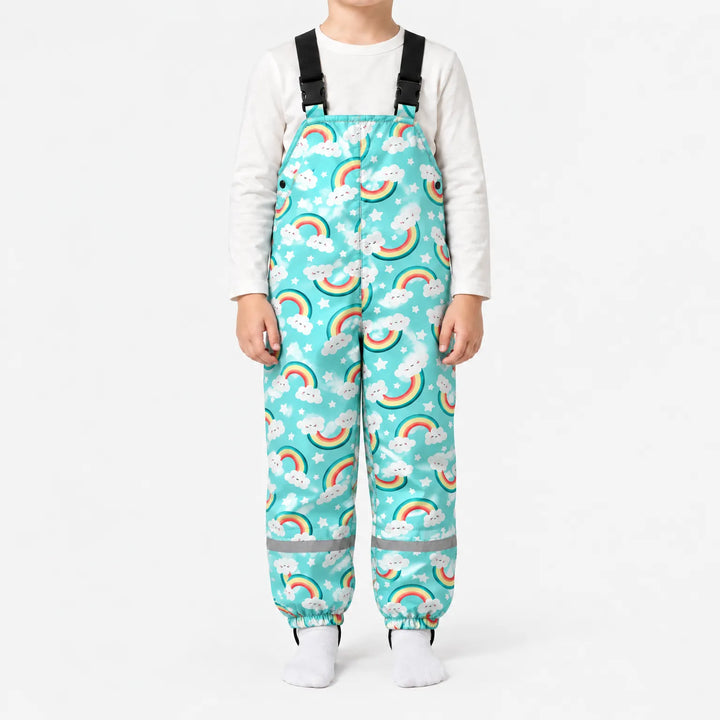 Child standing in turquoise dungarees printed with smiling rainbows, clouds and stars, with black buckled straps and elasticated ankle cuffs. 8