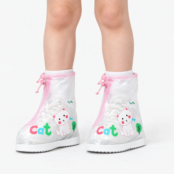 Child wearing clear shoe covers with pink trim and a white cat print over white sneakers, shown against a plain white background. 2