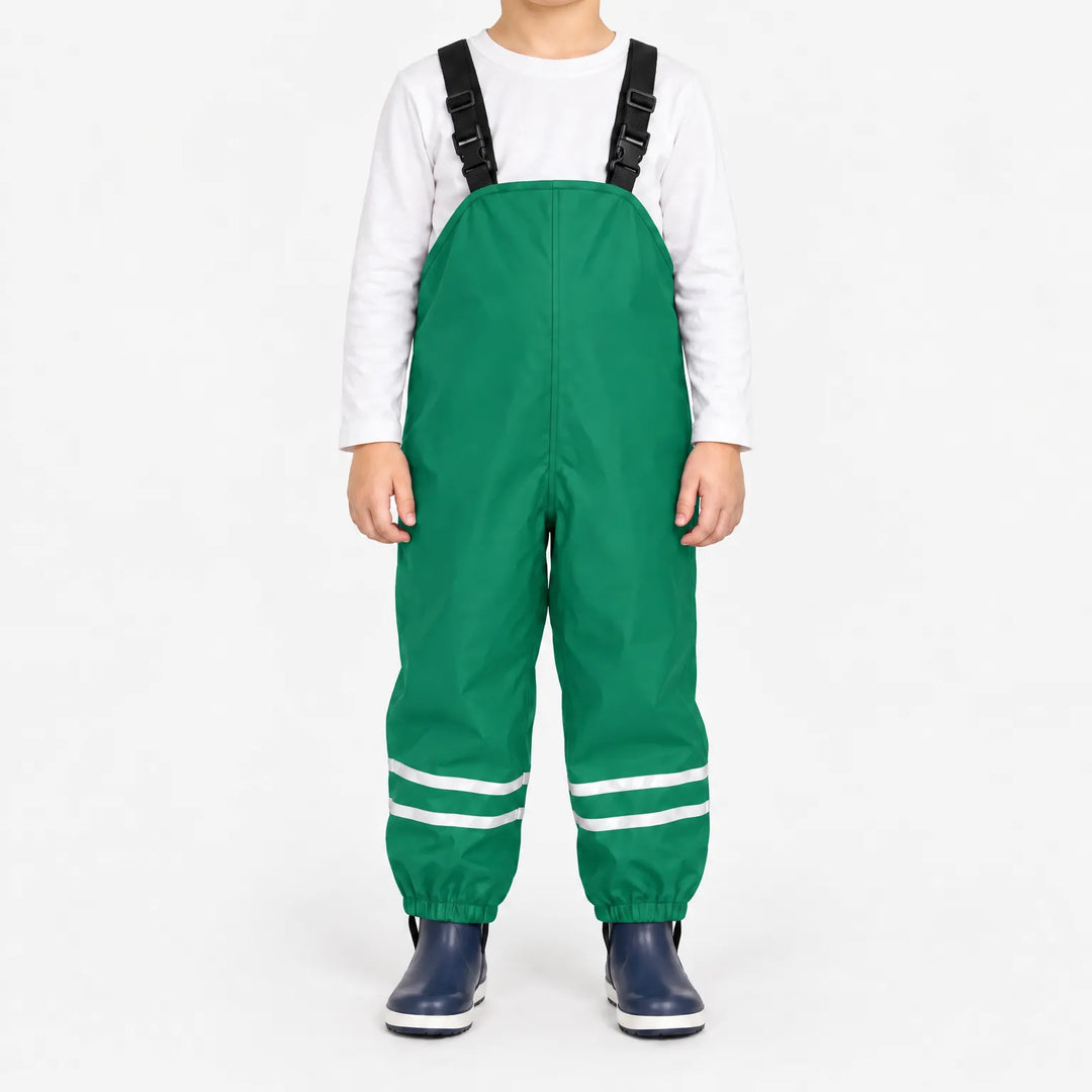 Child facing front in green waterproof dungarees with black adjustable straps, reflective ankle stripes and navy boots, white background. 10