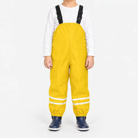 Child facing front in yellow waterproof dungarees with white top, reflective stripes on both legs and navy boots, plain white background. 14