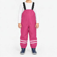 Child facing front in bright pink waterproof dungarees with reflective stripes on each leg and navy boots, plain white background. 9