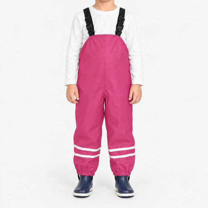 Child facing front in bright pink waterproof dungarees with reflective stripes on each leg and navy boots, plain white background. 9