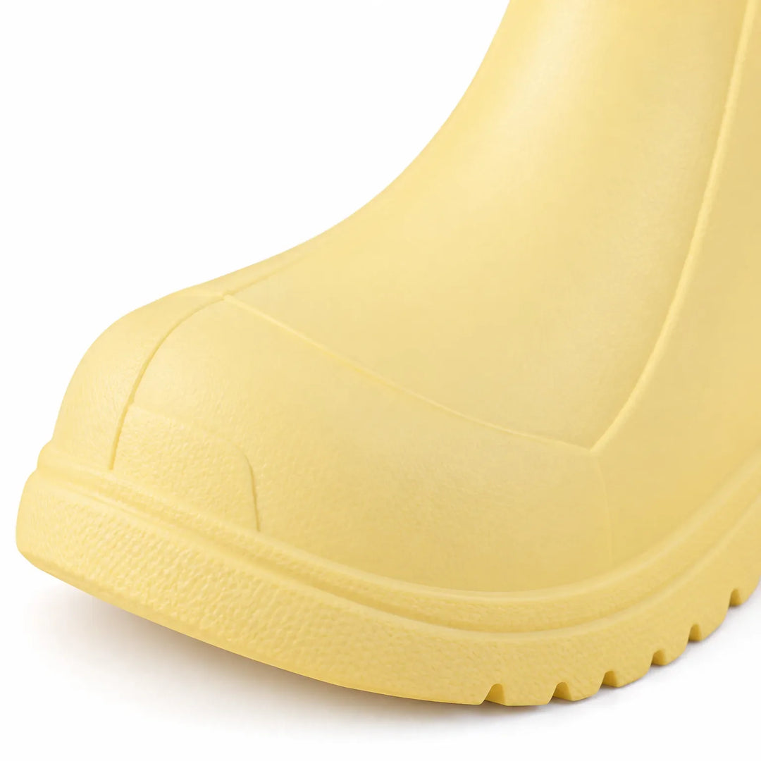 Close-up detail of a yellow welly toe, showing the textured toe cap and the grooved rubber sole edge. 6