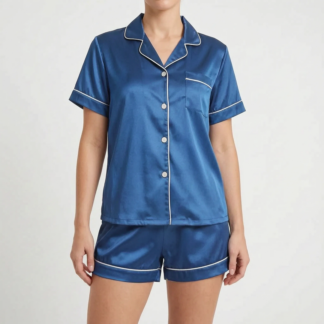 Front view of the blue satin pyjama set with white piping and pale buttons, worn by a model. 10