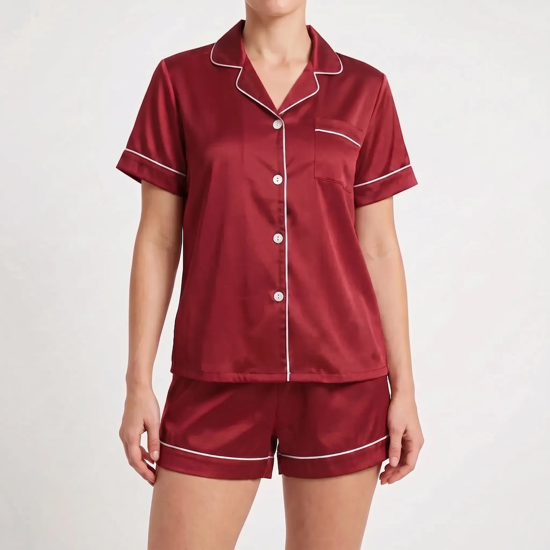 Front view of the burgundy red satin pyjama set with light piping and white buttons, worn by a model. 7