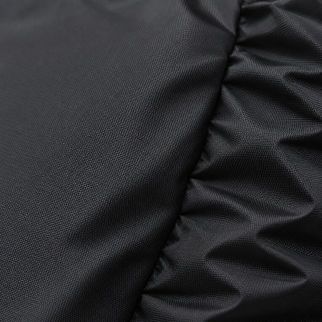 Close-up of the tightly woven black fabric, with a smooth panel on the left and gathered elastic folds on the right. 5
