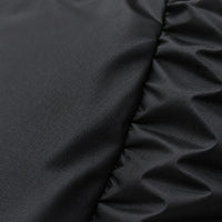 Close-up of the tightly woven black fabric, with a smooth panel on the left and gathered elastic folds on the right. 5