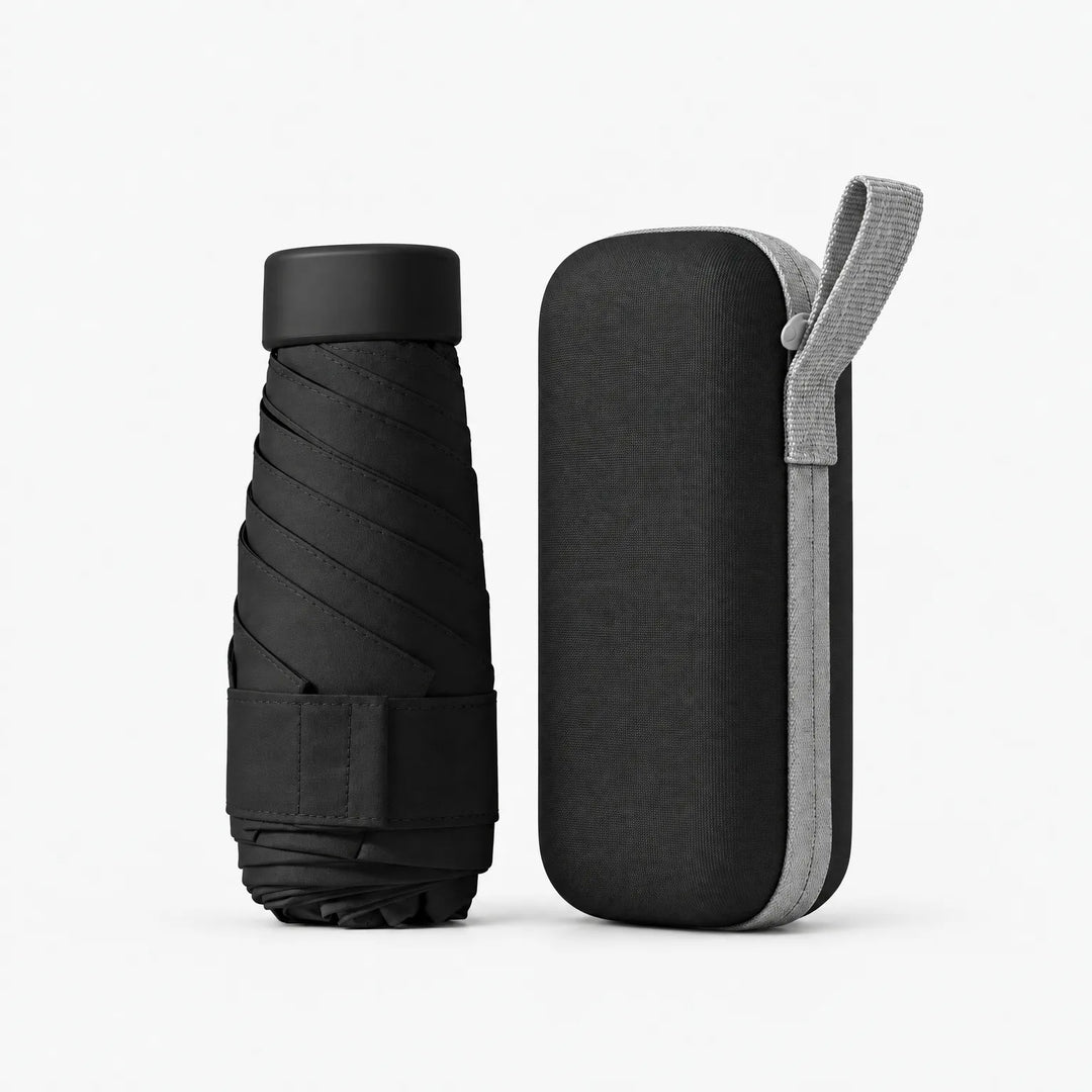 Black folded umbrella with black cap and strap beside a matching black hard zippered case with a light grey wrist loop, on white. 12