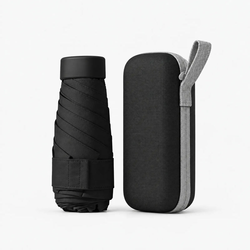 Black folded umbrella with black cap and strap beside a matching black hard zippered case with a light grey wrist loop, on white. 12
