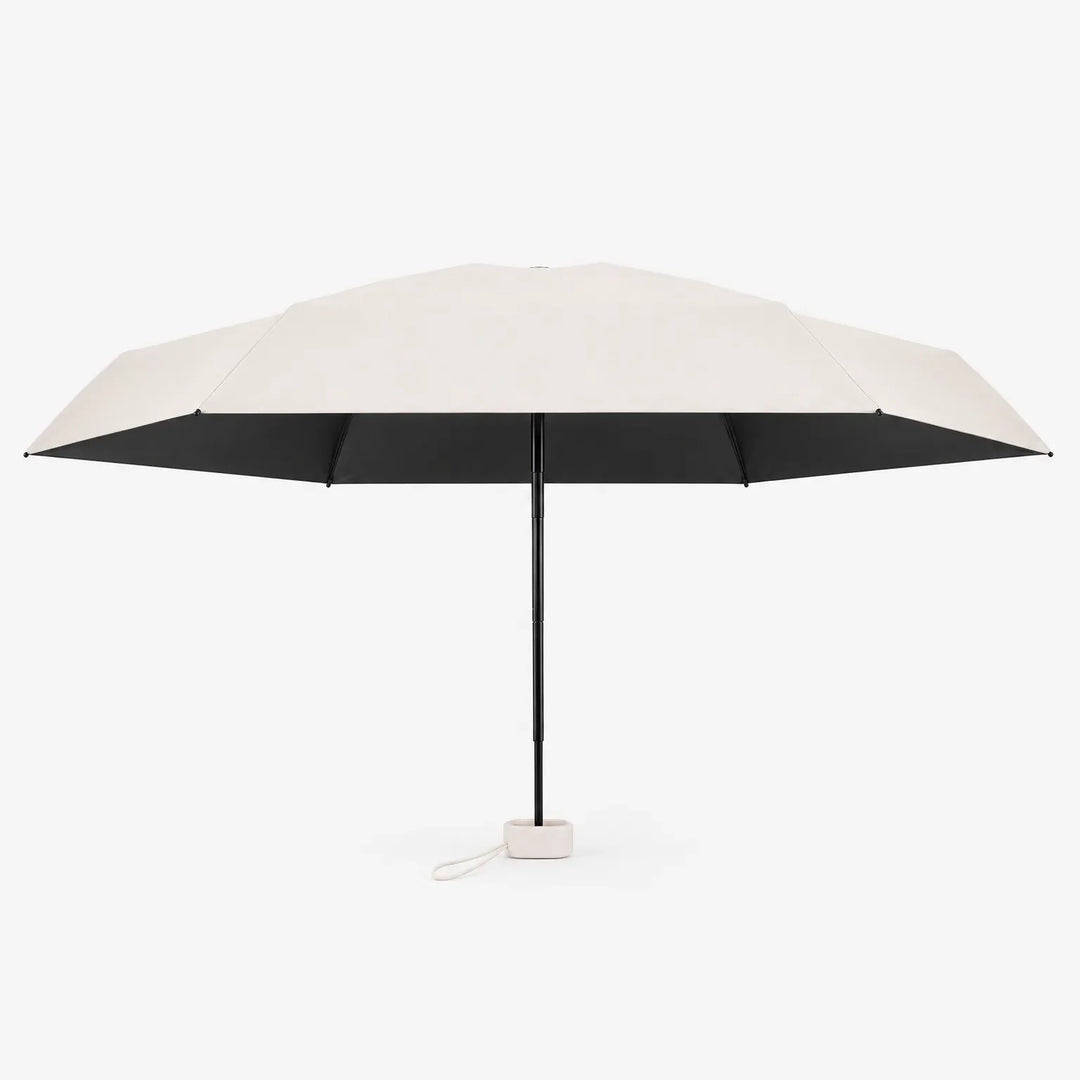 Open cream umbrella shown from the side against white, with a black underside, black shaft and a small cream cord loop at the handle. 4